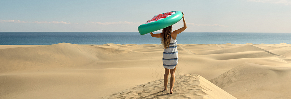Jente som går med oppblåsbar badeleke på stranden