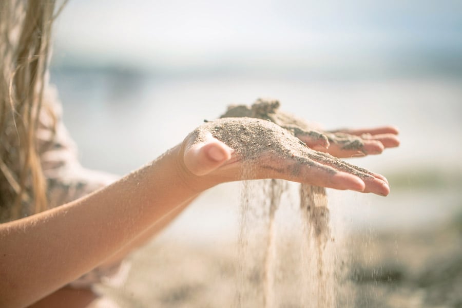 En hånd der sanden renner ut mellom fingrene